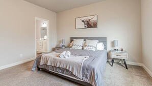 A bedroom with a bed, nightstands, a mirror, and a door leading to another room. - Cozy 3bd/2ba House in Horace (Horace)