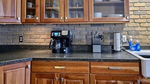 A kitchen with wooden cabinets, a coffee maker, and a knife block on the counter. - Downtown Depot - Unit 5 (Fargo)