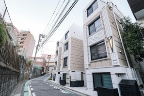 A narrow urban street with modern buildings, a green bike lane, and a clear sky. - Mi-Hotel Qualia Shinjuku (Tokyo)