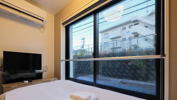 A hotel room with a bed, a TV, and a large window with a view of buildings. - Mi-Hotel Qualia Shinjuku (Tokyo)