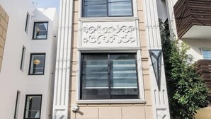 A building with a central window flanked by two smaller windows, a decorative facade, and a balcony with greenery. - Mi-Hotel Qualia Shinjuku (Tokyo)