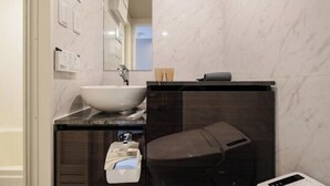 A bathroom with a white sink, dark countertop, and a toilet. - Mi-Hotel Qualia Shinjuku (Tokyo)