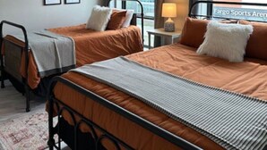 Una camera d'albergo con due letti, una ventola a soffitto, quadri appesi alle pareti e vista sull'esterno.
