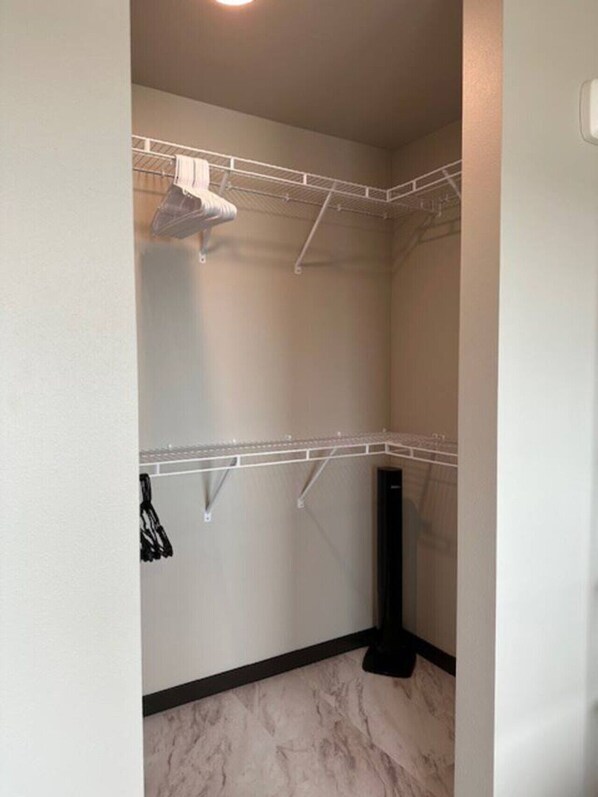 A corner closet with a white metal shelving unit, a black floor lamp, and a marble floor. - Come, Stay, Relax - The Lights (West Fargo)