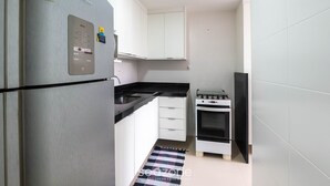 Eine kleine Küche mit integriertem Kühlschrank, einem Herd und weißen Schränken.