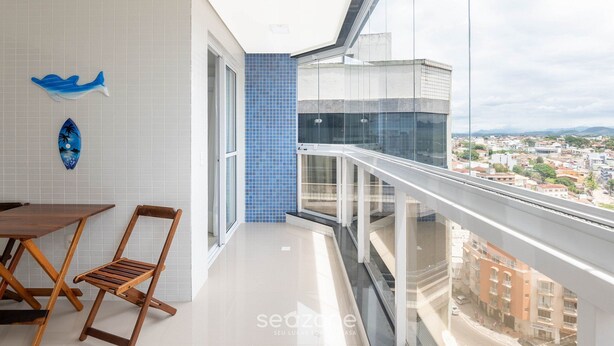 Ein Balkon mit Blick auf die Stadt, eine Essecke mit Tisch und Stühlen sowie dekorative Wandbilder.