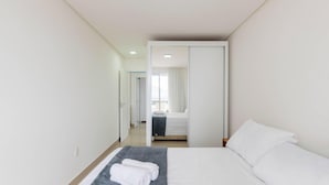 Ein Hotelzimmer mit einem Bett, einem grauen Teppich und einem weißen Handtuch auf dem Bett.