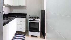 A compact kitchen with a built-in refrigerator, a stove, and white cabinetry.