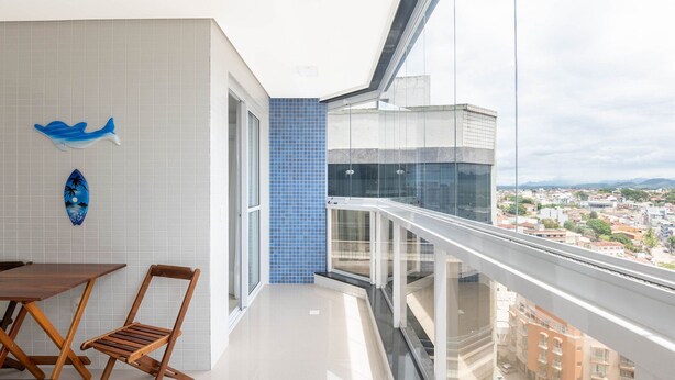 A balcony with a city view, a dining area with a table and chairs, and decorative wall art.