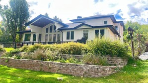 Ein zweistöckiges Haus mit einer Steinmauer und einem gepflegten Rasen.