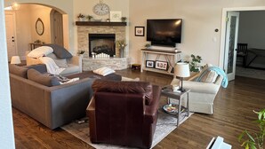 Ein Wohnzimmer mit Kamin, Sofas, Fernseher und einer Wanduhr.