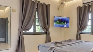 Ein Schlafzimmer mit Bett, Vorhängen, einem Fernseher und einer Klimaanlage.