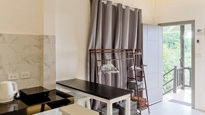 Eine moderne Küche mit schwarzer Arbeitsplatte, einem weißen Tisch und einem grauen Vorhang.