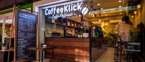 A CoffeeKlick café with a wooden counter, menu board, and seating area.