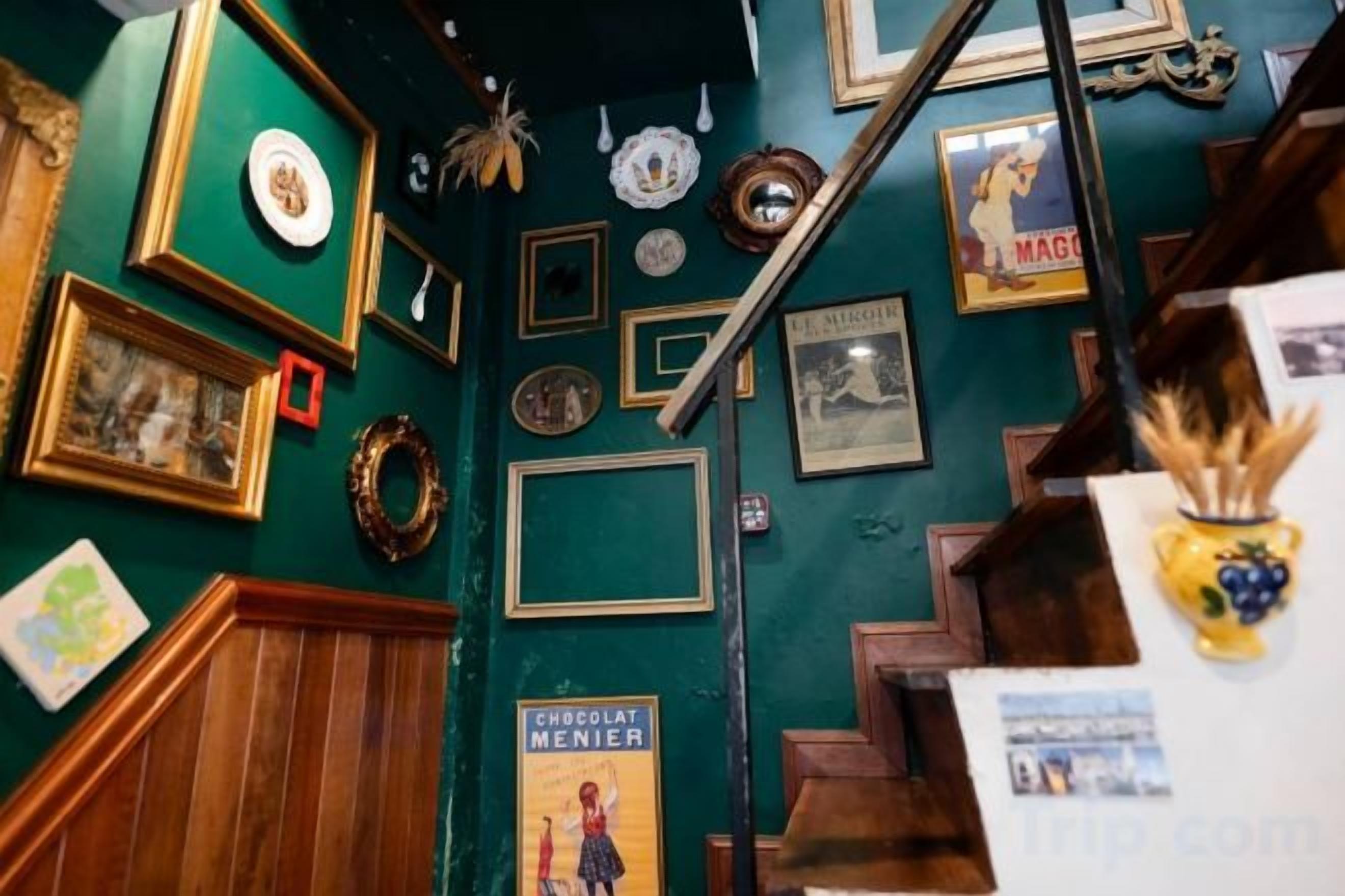 A room with a staircase, wooden paneling, and various framed items on the walls.