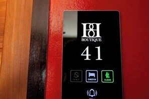 Eine digitale Anzeige mit dem Text 'BOUTIQUE 41' und Symbolen für 'Bitte nicht stören', 'Check-in', 'Reinigung' und eine Klingel.