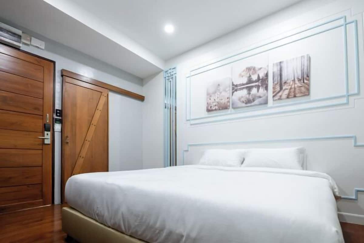 Une chambre à coucher avec un lit, une porte en bois et des œuvres d’art accrochées au mur.