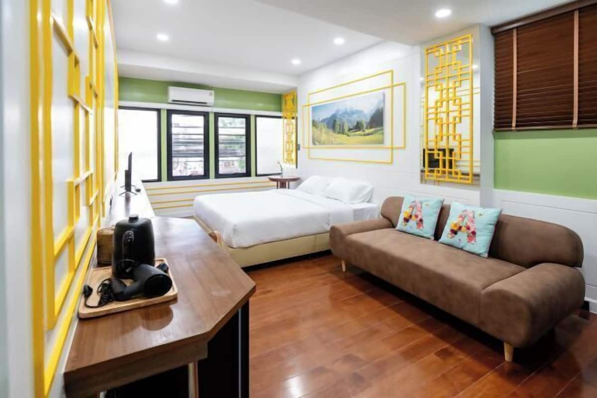 Une chambre d’hôtel avec un lit, un canapé, un bureau en bois avec une machine à café et une fenêtre donnant sur un paysage agréable.