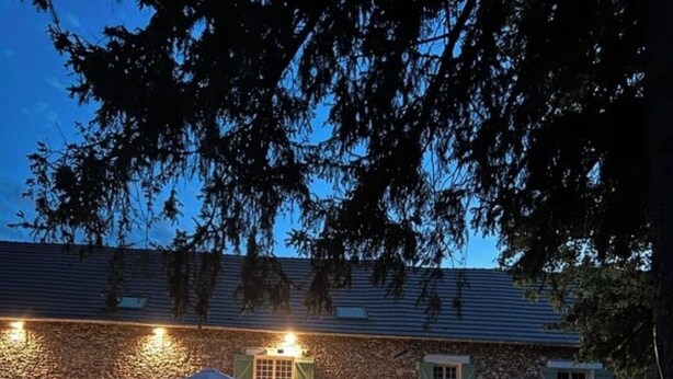 A stone building with a well-lit outdoor seating area and a covered patio. - Large house with swimming pool - sleeps 13, sleeps 25 - near Paris (rebais)