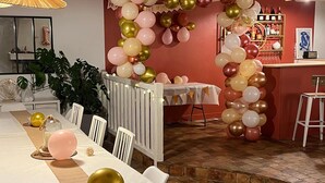 A long dining table with white chairs, surrounded by a wall decorated with balloons and a bar area with shelves of bottles. - Large house with swimming pool - sleeps 13, sleeps 25 - near Paris (rebais)
