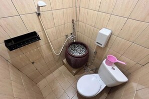 A small bathroom with a toilet, a bidet, and a soap dispenser. - New Panjang Jiwo Resort Syariah (Sukaraja)