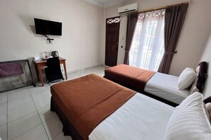 A hotel room with two beds, a desk with a chair, a TV mounted on the wall, and an air conditioning unit. - New Panjang Jiwo Resort Syariah (Sukaraja)