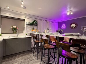 Una cocina moderna con encimera de mármol, taburetes de bar y una estantería empotrada para vinos.