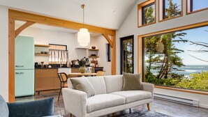 A modern living room with a sofa, a dining table, and a kitchen in the background. - Fogged Inn (Ucluelet)