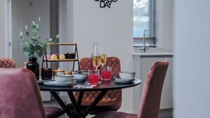 Ein Esstisch mit Kerze, Pflanze und einem Glas Wein.