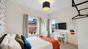 Ein modernes Schlafzimmer mit Bett, Schreibtisch und Fernseher.