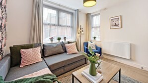Ein modernes Wohnzimmer mit einer Couch, einem Couchtisch und einem Fenster mit Vorhängen.