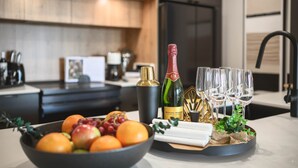 A modern kitchen with a fruit bowl, a bottle of champagne, and glasses on the counter. - Hôtel à la maison - Luxe Alpine MSA (Beaupré)