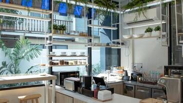 A modern kitchen with built-in appliances, wooden bar stools, and hanging plants.