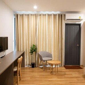 Una habitación con escritorio, silla, planta en maceta y una puerta.