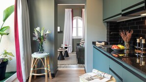 Una cocina moderna con armarios oscuros, una encimera negra y un ventanal con cortinas blancas.