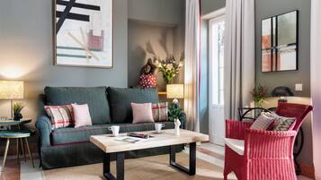 Un salon comprenant un canapé, une table basse, un fauteuil en osier rouge et des œuvres d’art accrochées aux murs.