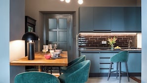 Una cocina moderna con armarios oscuros, un salpicadero de ladrillo y una mesa de comedor de madera con sillas verdes.