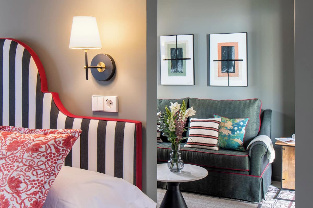 A modern room with a striped headboard, a round table, and a sofa with decorative pillows.