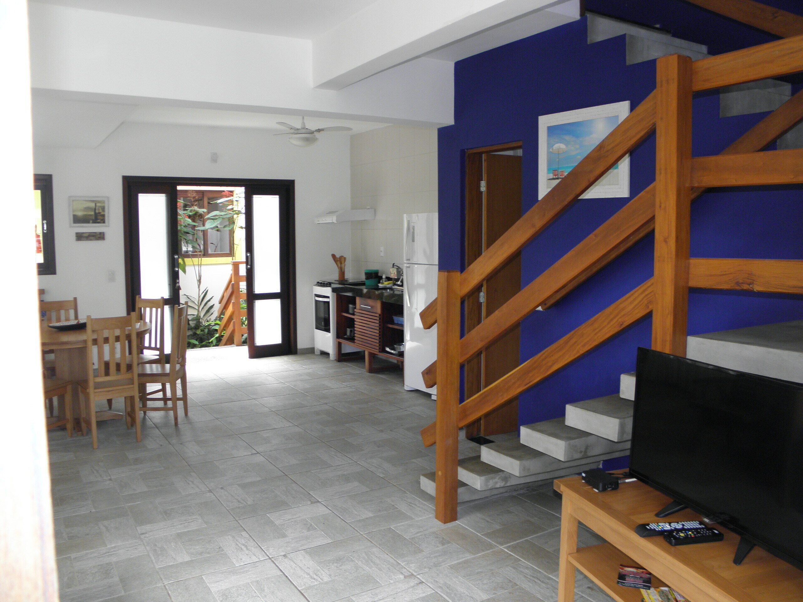 Una sala de estar con televisor, muebles de madera y una escalera.