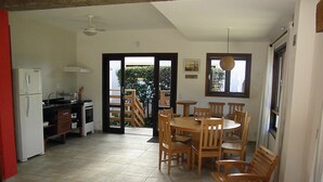 Una cocina amplia con comedor, refrigerador y una mesa de madera con sillas.