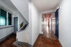 A hallway with a staircase, a door, and a blue door at the end. - Sindang M (Seoul)