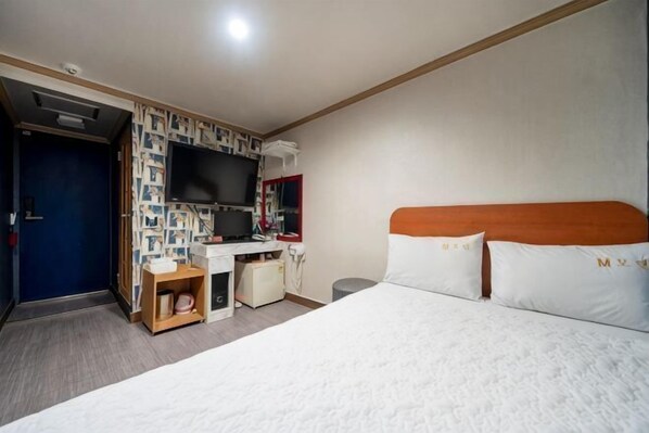 A hotel room with a bed, a desk, a television, and a wardrobe. - Sindang M (Seoul)