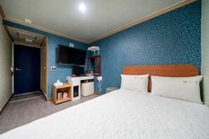 Una habitación de hotel con cama, escritorio con computadora, televisor y baño.