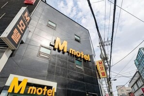Un edificio con letrero que dice 'M motel', varias ventanas y líneas eléctricas visibles.