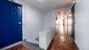 A hotel hallway with a blue door, a white bench, and a wooden floor. - Sindang M (Seoul)
