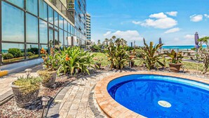 A swimming pool surrounded by potted plants and a modern building with large windows. - Modern Studio with 2 Queen Beds | Partial Ocean View | Pool & Beach Access (Daytona Beach)