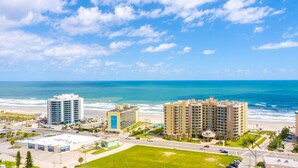 A coastal hotel with multiple high-rise buildings, a beach, and a parking area. - Modern Studio with 2 Queen Beds | Partial Ocean View | Pool & Beach Access (Daytona Beach)