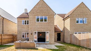 A two-story brick house with a patio area and a fenced backyard.