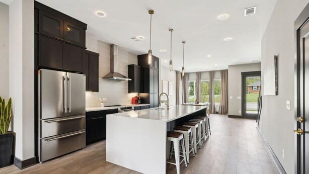Een moderne keuken met een centraal eiland, roestvrijstalen apparatuur en hanglampen.