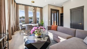 A modern living room with a grey sofa, a coffee table, and a dining area with a table and chairs. - East Nash Luxury Escape w/Rooftop Deck-Sleeps 12! (Nashville)